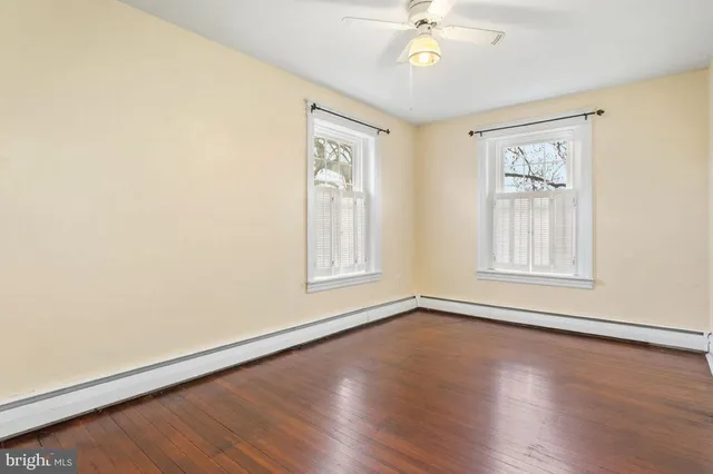 an empty room with wooden floor chandelier fan and windows
