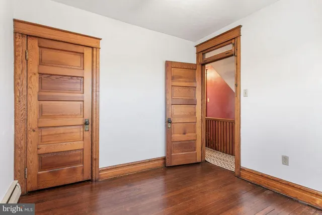 an empty room with wooden floor closet and windows
