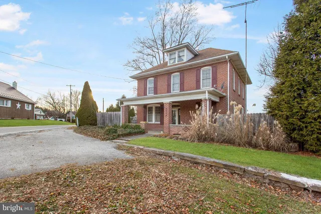 a front view of a house with a garden and trees