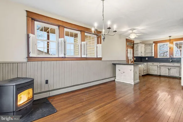a view of an empty room with window wooden floor and kitchen view