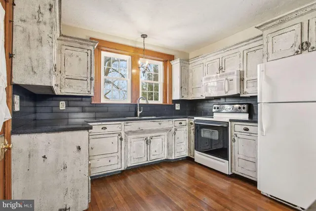 a kitchen with granite countertop white cabinets and white appliances