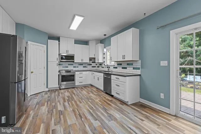 a kitchen with white cabinets stainless steel appliances and a window