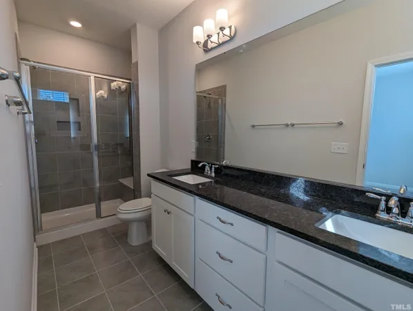 a bathroom with a granite countertop sink a toilet a mirror and shower