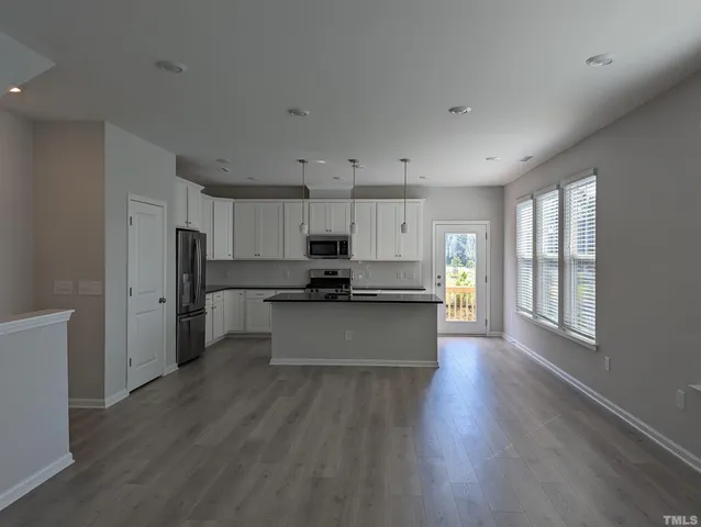 a large kitchen with stainless steel appliances wooden floors and large window
