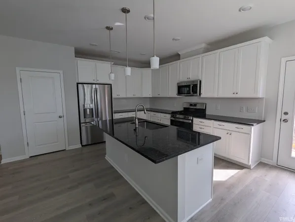 a kitchen with granite countertop a refrigerator a sink and dishwasher with wooden floor