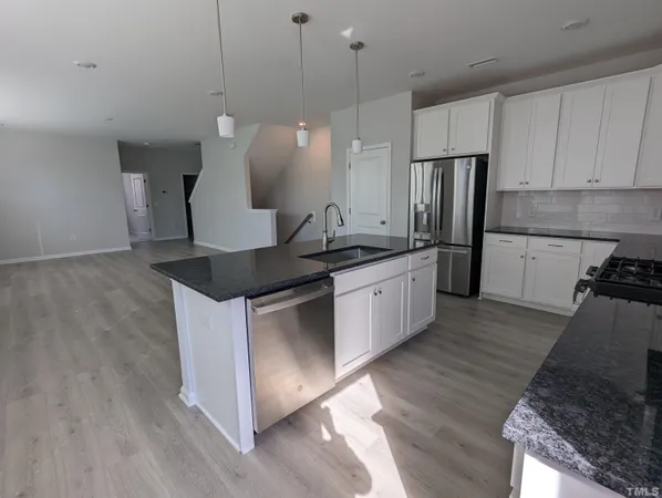 a kitchen with stainless steel appliances granite countertop a sink a stove a refrigerator and island with wooden floor