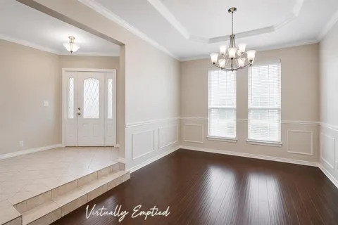 an empty room with wooden floor chandelier and windows