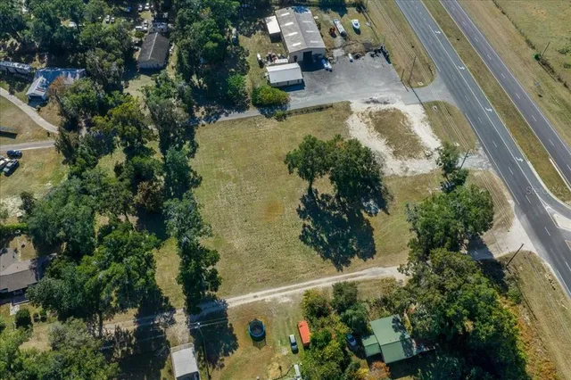 an aerial view of a residential houses with outdoor space and trees