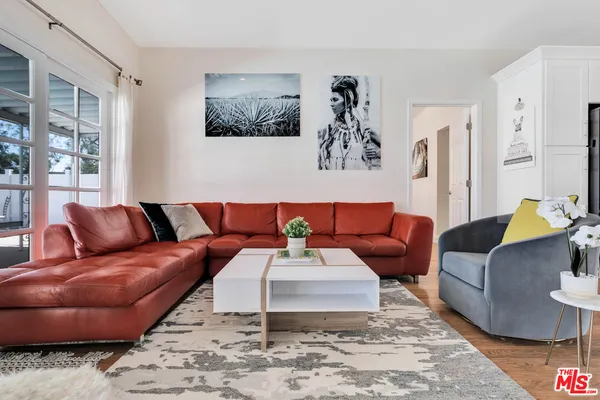 a living room with furniture kitchen view and a large window