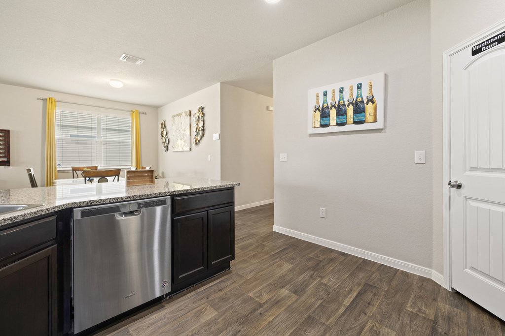 204 Rochester Lane Hutto, TX 78634 - Photo 10 of 40 Kitchen with stainless steel dishwasher, light stone counters, and dark wood-type flooring