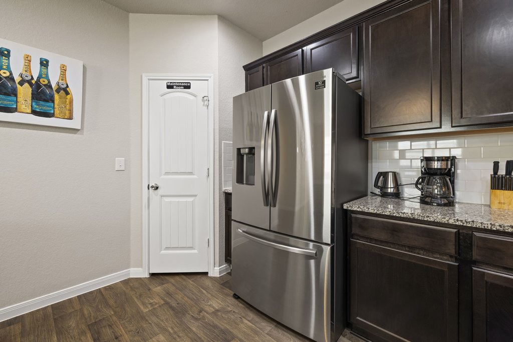 204 Rochester Lane Hutto, TX 78634 - Photo 11 of 40 Kitchen featuring stainless steel fridge with ice dispenser, light stone countertops, dark wood finish cabinets, dark wood-style flooring, and tasteful backsplash
