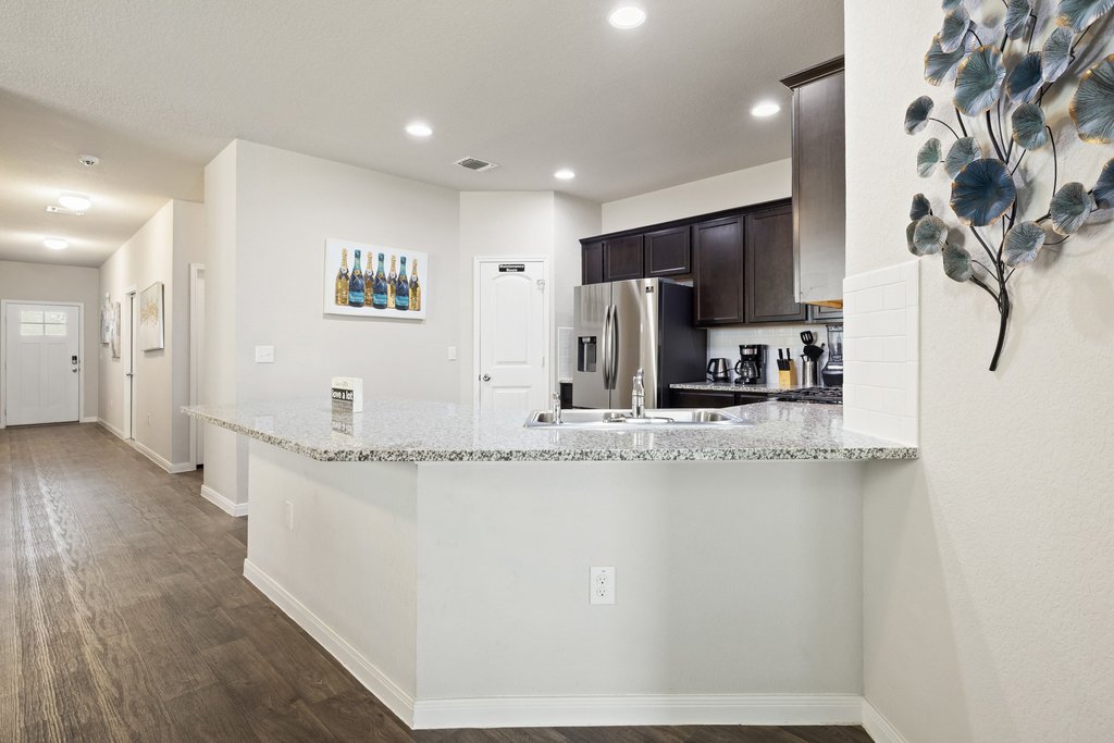 204 Rochester Lane Hutto, TX 78634 - Photo 13 of 40 Kitchen featuring a peninsula, stainless steel fridge with ice dispenser, dark wood-style flooring, dark wood finish cabinetry, and recessed lighting