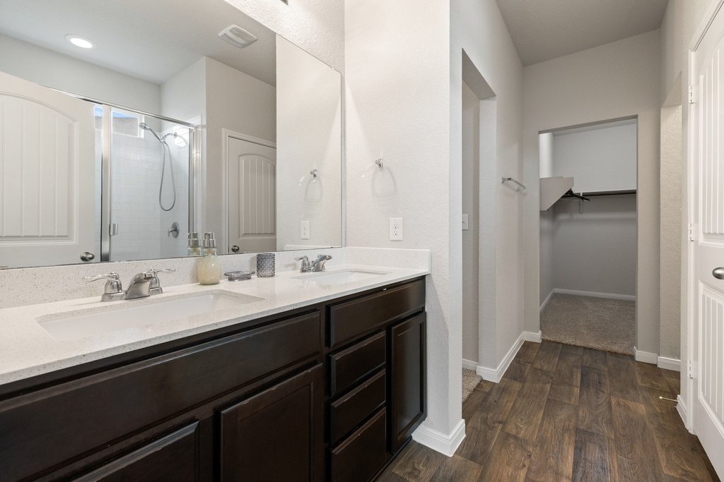 204 Rochester Lane Hutto, TX 78634 - Photo 23 of 40 Bathroom with a walk in closet, double vanity, a stall shower, and dark wood finished floors
