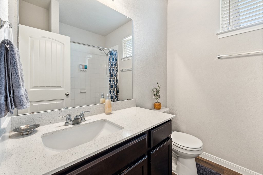 204 Rochester Lane Hutto, TX 78634 - Photo 29 of 40 Bathroom featuring a textured wall, vanity, curtained shower, and wood finished floors