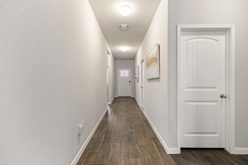 204 Rochester Lane Hutto, TX 78634 - Photo 6 of 40 Hallway with baseboards and dark wood-style floors