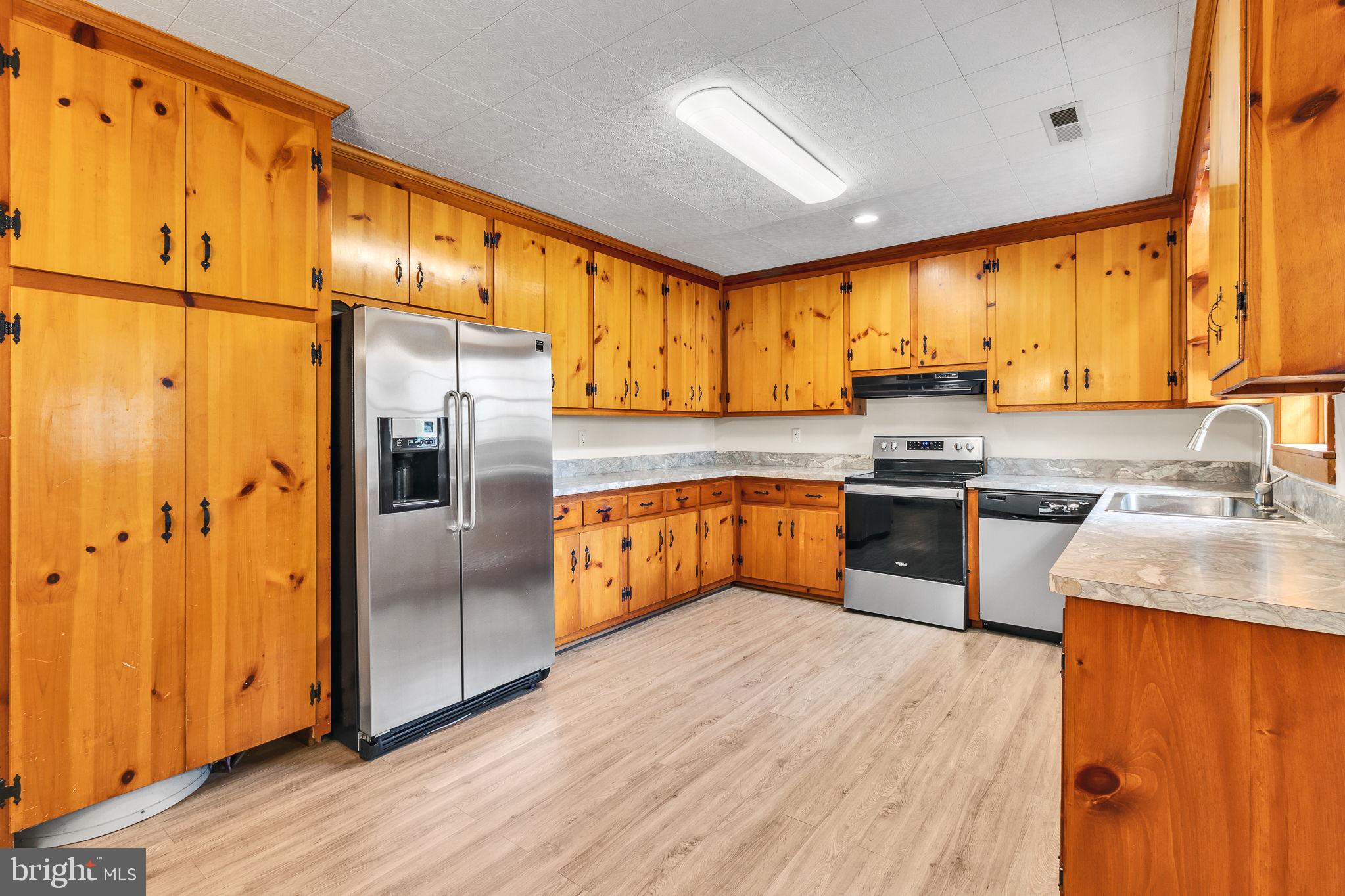 239 Lane Road Reedville, VA 22539 - Photo 8 of 61 a kitchen with stainless steel appliances granite countertop a refrigerator a sink dishwasher and wooden cabinets with wooden floor