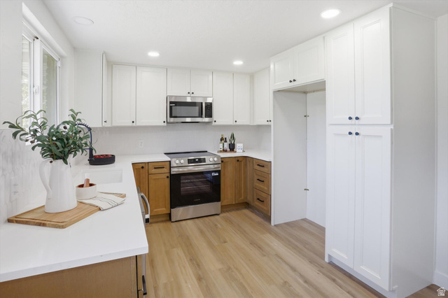 810 East Maple Street Mapleton, UT 84664 - Photo 11 of 49 Modern kitchen featuring white shaker cabinetry, stainless steel appliances, light wood-finish flooring, white countertops, and a full-height tile backsplash
