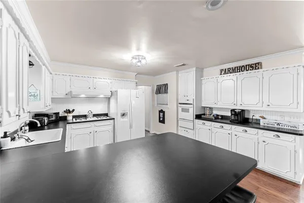 a large kitchen with cabinets wooden floor and stainless steel appliances