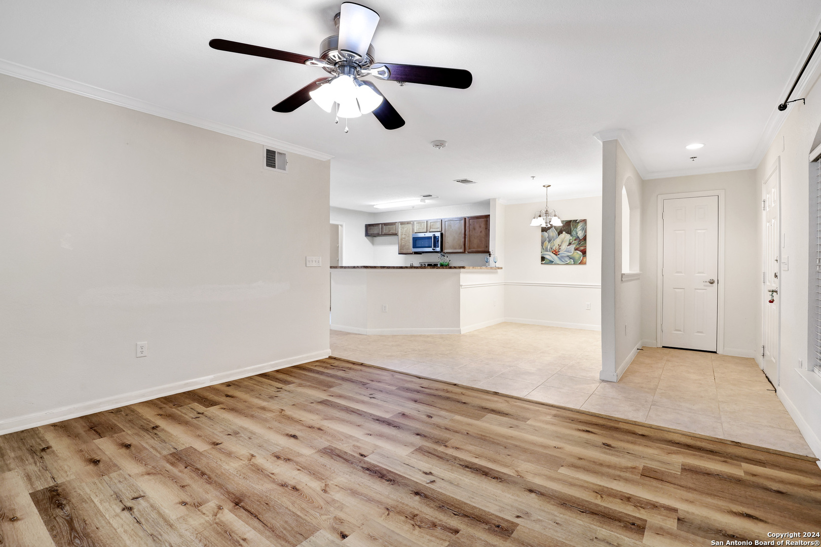 7323 Snowden Road, Unit 3108 San Antonio, TX 78229 - Photo 11 of 31 an empty room with wooden floor ceiling fan and kitchen view