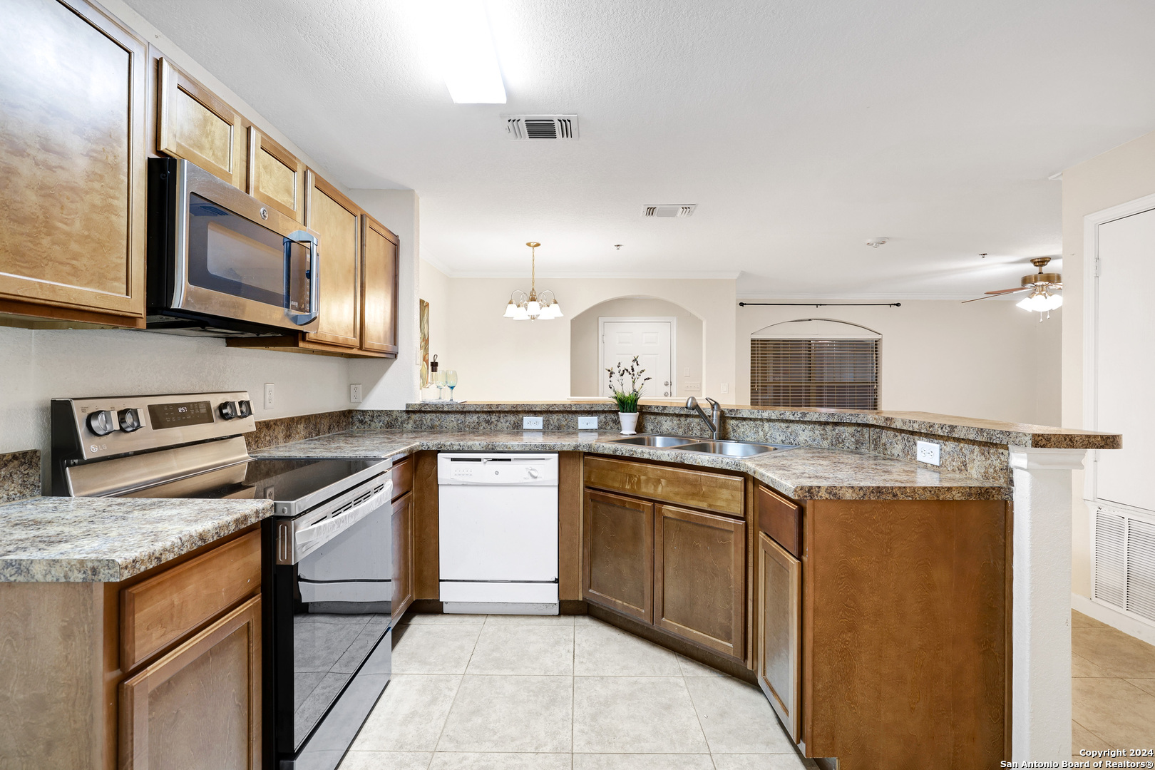 7323 Snowden Road, Unit 3108 San Antonio, TX 78240 - Photo 17 of 34 a kitchen with stainless steel appliances granite countertop a stove top oven a sink dishwasher and a refrigerator with wooden cabinets