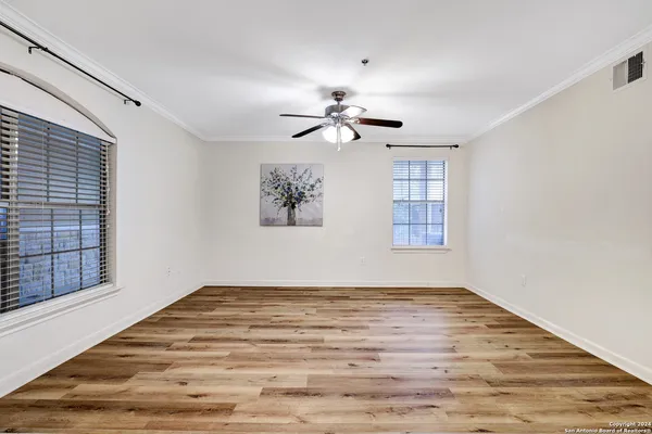 a view of empty room with wooden floor and fan