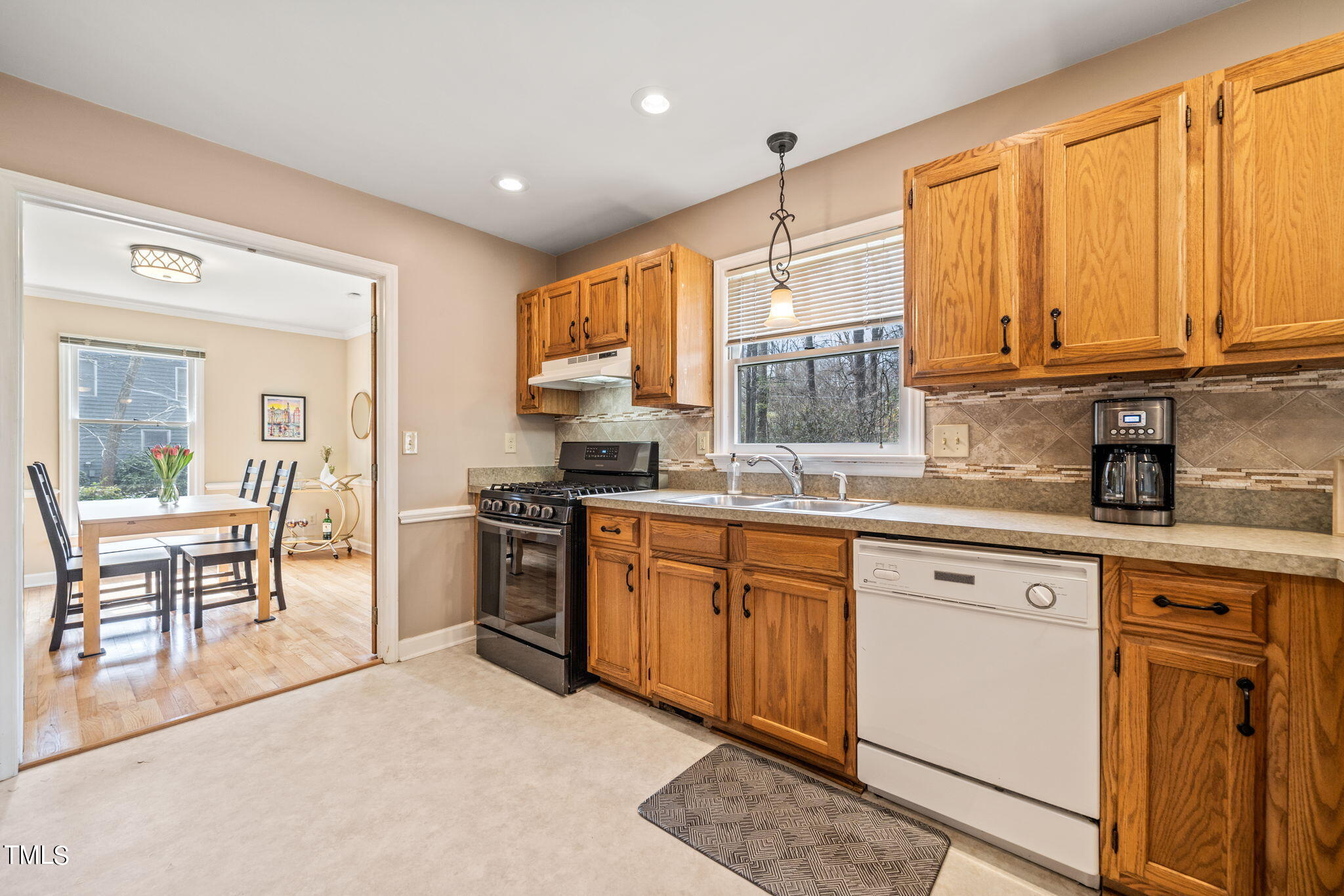 2415 Tryon Road Durham, NC 27705 - Photo 10 of 39 a kitchen with stainless steel appliances granite countertop a stove top oven a sink dishwasher a dining table and chairs with wooden floor