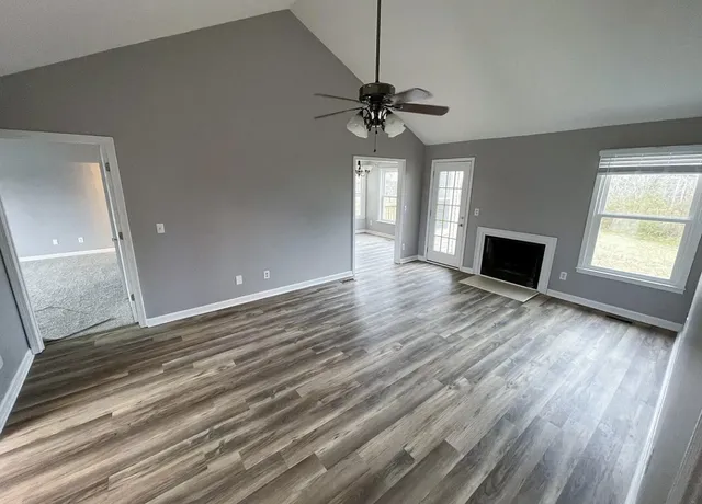 a view of an empty room with window and wooden floor