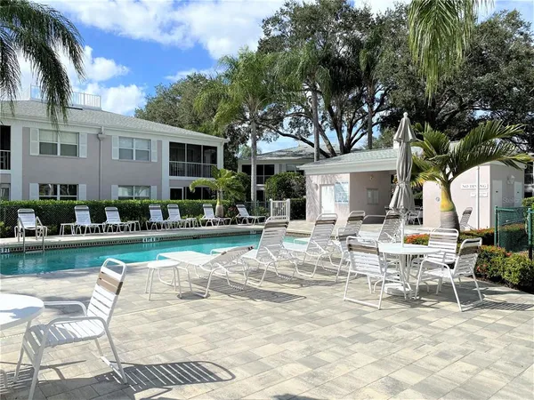 a view of a patio with dining table and chairs with plants and palm trees