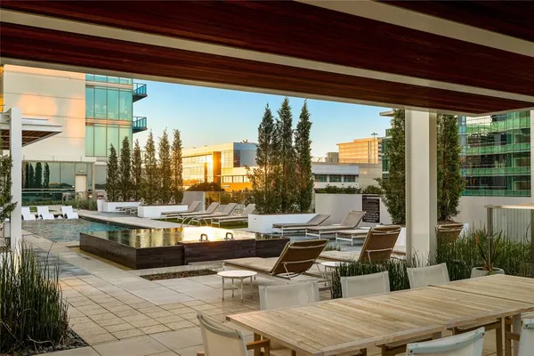 a living room with couches a table and chairs with potted plants