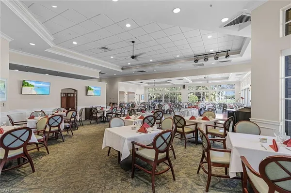 a room with lots of chairs a chandelier and a projector screen