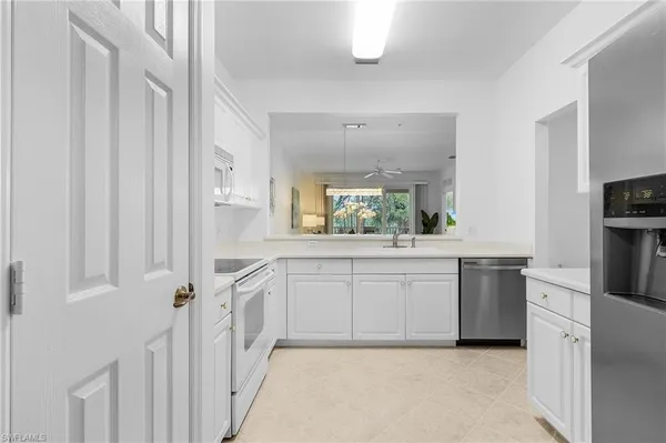 a large white kitchen with a sink and dishwasher a stove top oven with wooden floor