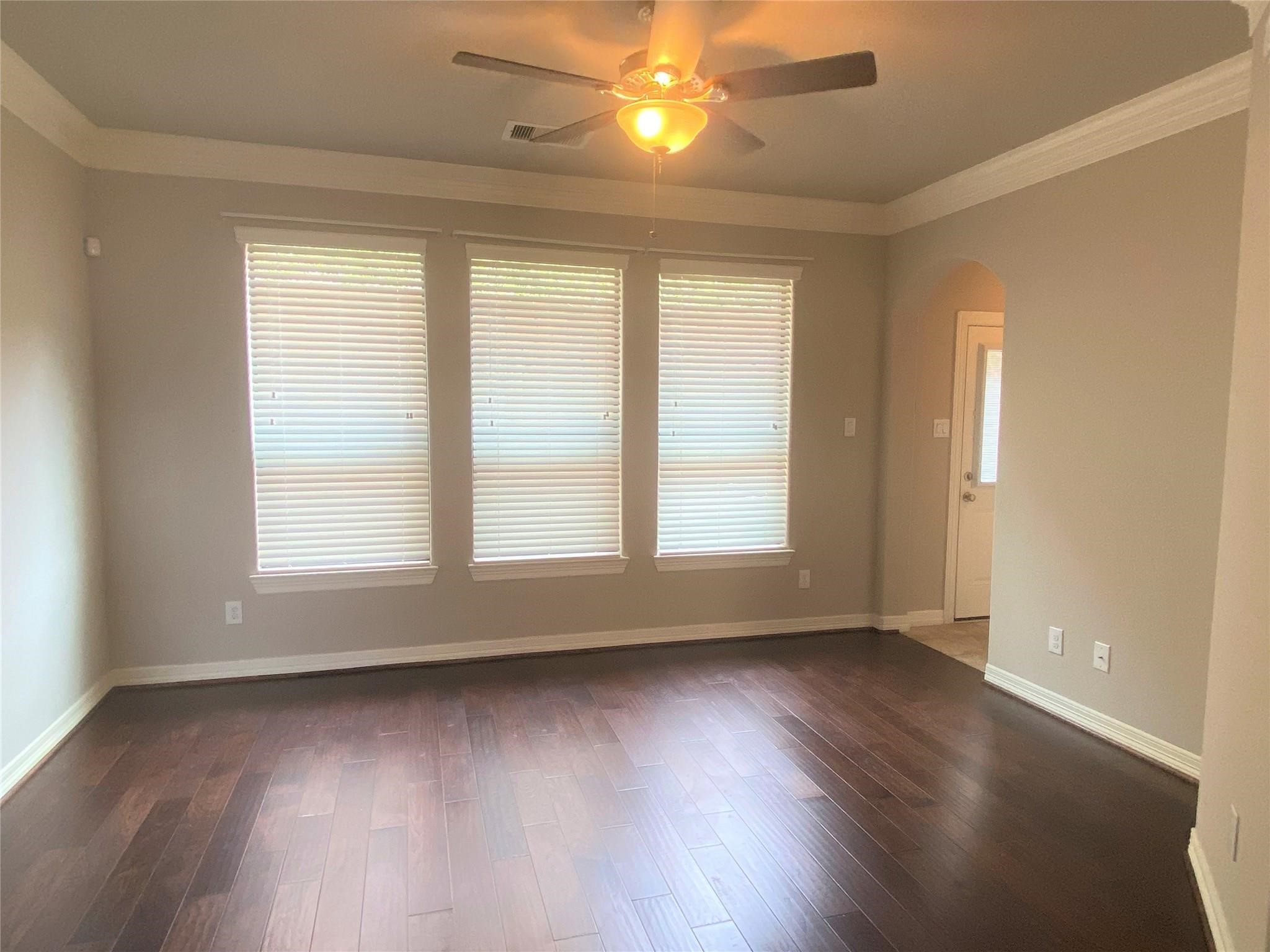 3002 Soutine Street Houston, TX 77021 - Photo 3 of 12 an empty room with wooden floor and windows with curtains