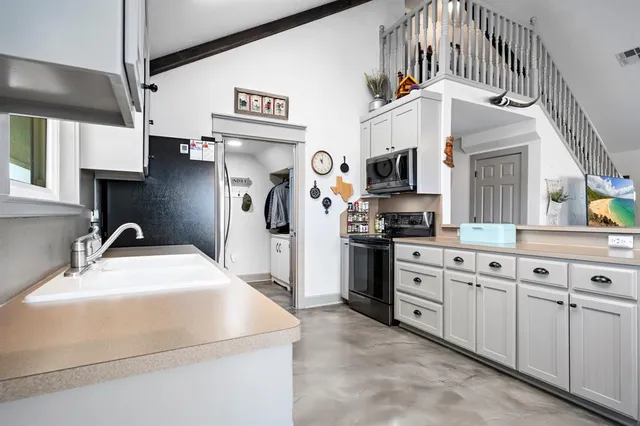 a kitchen with stainless steel appliances granite countertop a refrigerator a sink dishwasher and white cabinets next to a window