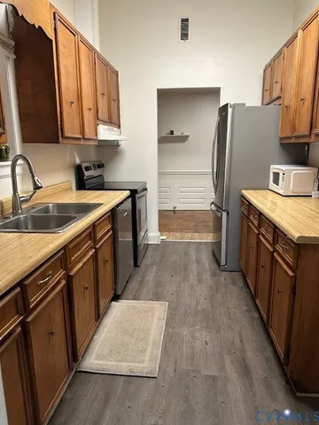 a kitchen with stainless steel appliances granite countertop a refrigerator a stove and a sink with wooden cabinets