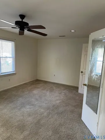 an empty room with a ceiling fan and windows