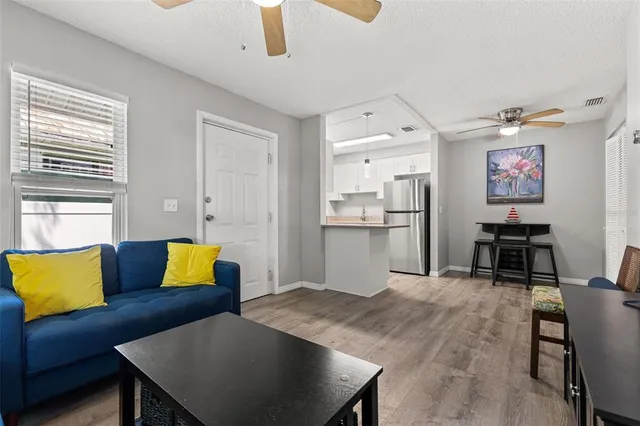 a living room with stainless steel appliances furniture and a kitchen view