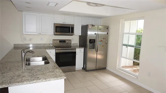 a kitchen with stainless steel appliances granite countertop a refrigerator a stove and a sink