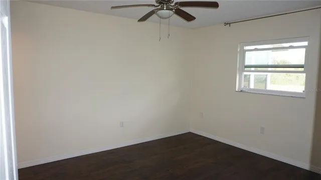 an empty room with a window and a fan