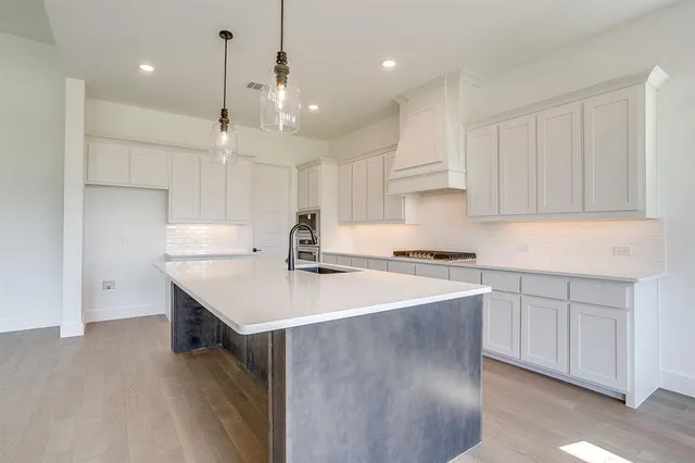 a kitchen with a sink a stove a refrigerator and white cabinets