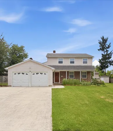 a house that is sitting in the grass with large trees