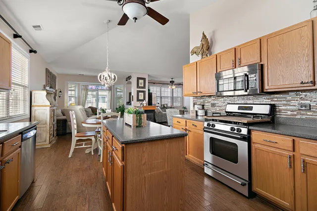 a kitchen with stainless steel appliances granite countertop a stove top oven a sink dishwasher a dining table and chairs with wooden floor