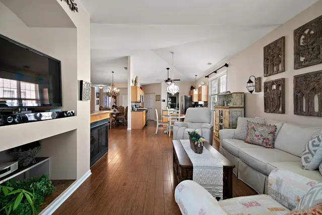 a living room with furniture kitchen view and a wooden floor