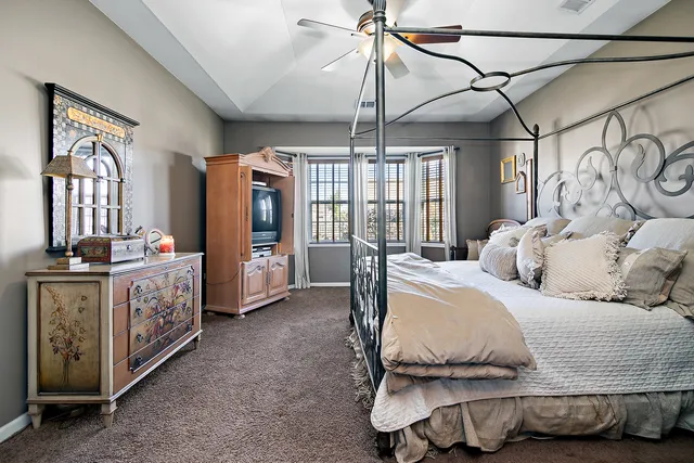 a bedroom with a bed next to a window and a chandelier