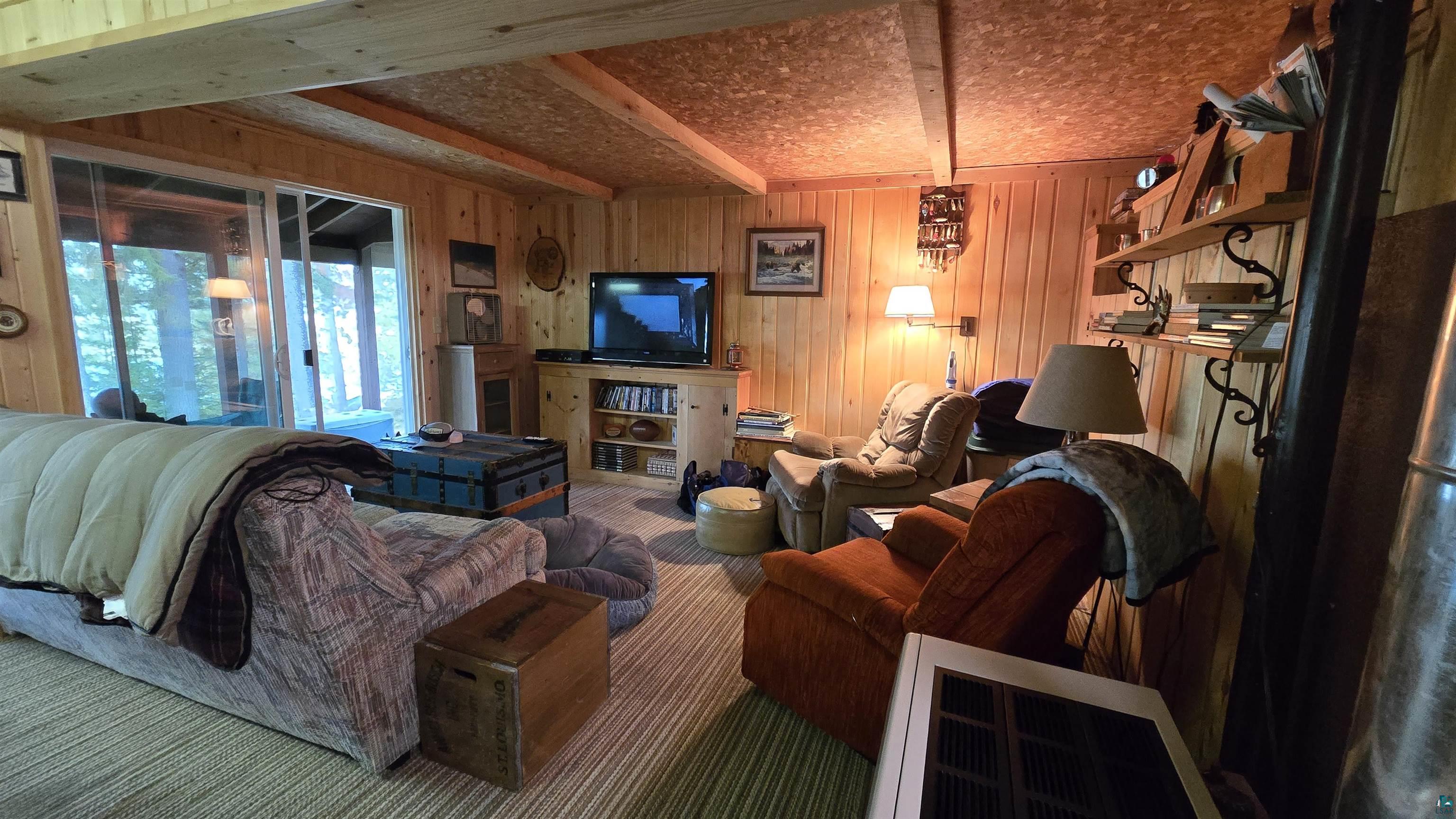 7178 Gold Mine Road Orr, MN 55771 - Photo 15 of 36 Living area with beamed ceiling, wooden walls, and carpet floors