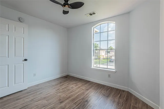 a view of empty room with wooden floor and fan