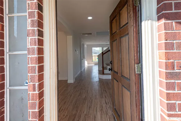 a view of a hallway with wooden floor and windows