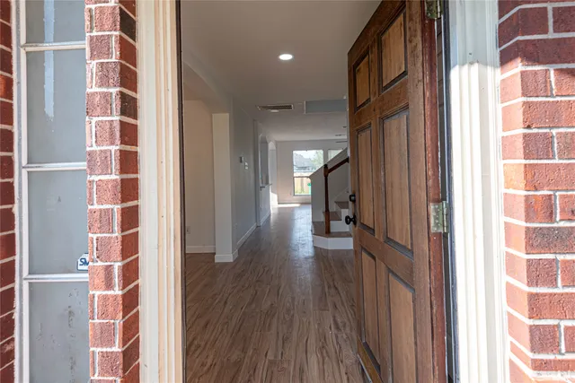 a view of a hallway with wooden floor and windows