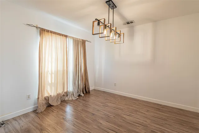 a view of empty room with wooden floor and windows