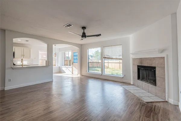 a view of an empty room with wooden floor and a fireplace
