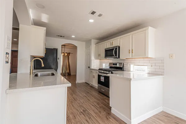a kitchen with granite countertop a sink stove and refrigerator